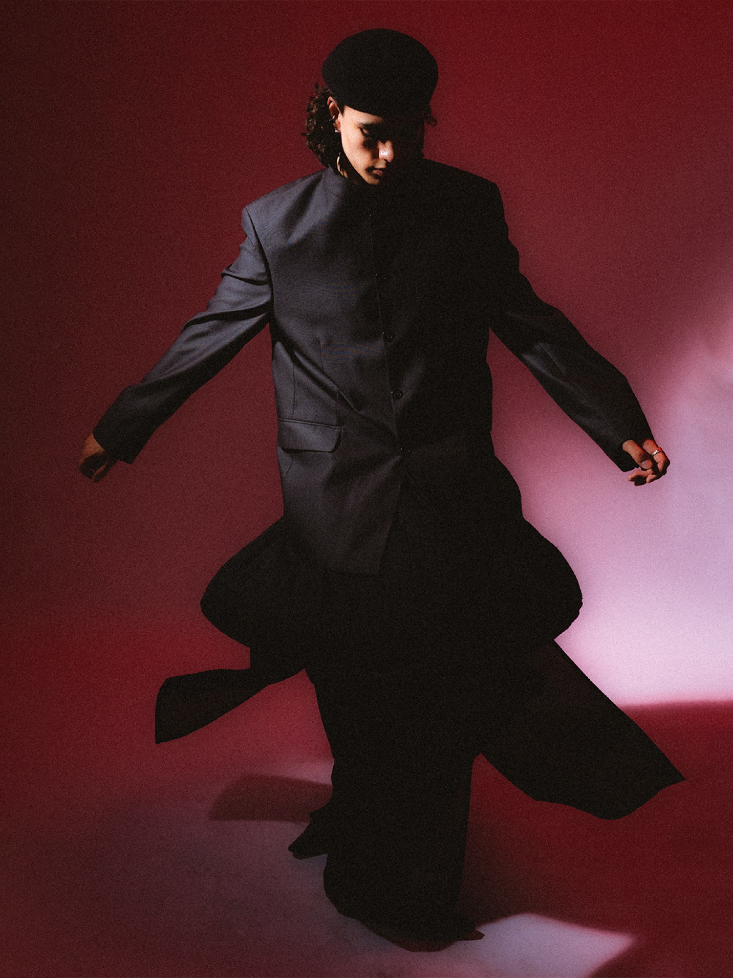 Model moving in a black layered suit under red light