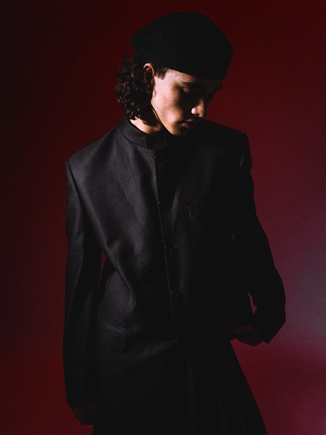 Close portrait in black tailoring and a beret against red light