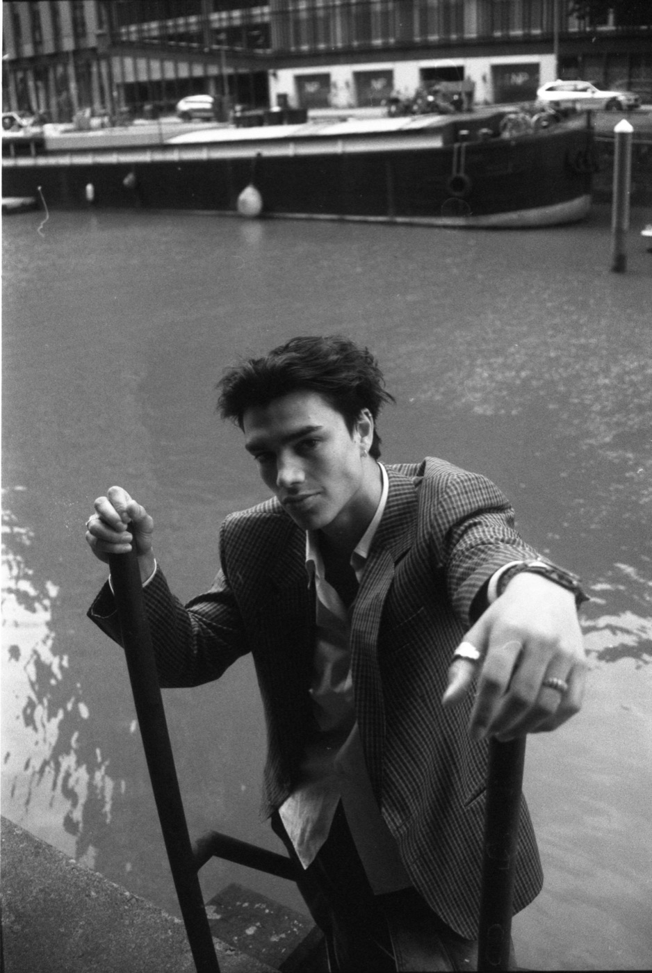 Jules Bouwens seated by the water in a checked blazer