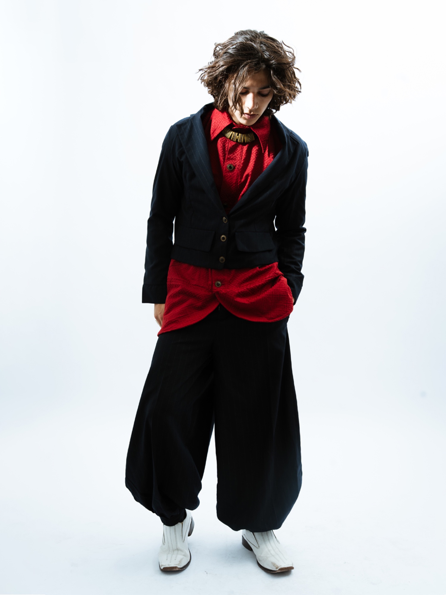 Model wearing a red blouse with black cropped jacket and wide trousers