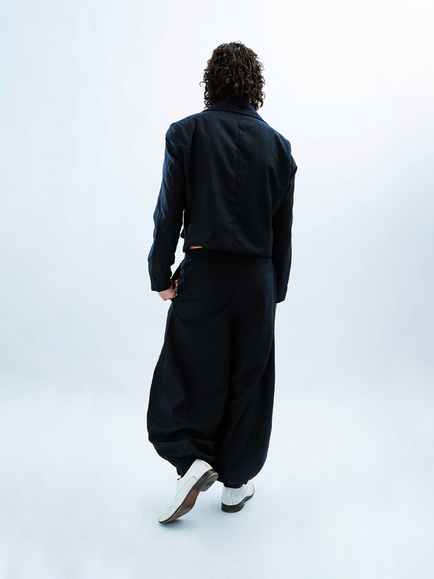 Back view of a cropped pinstripe jacket and wide trousers