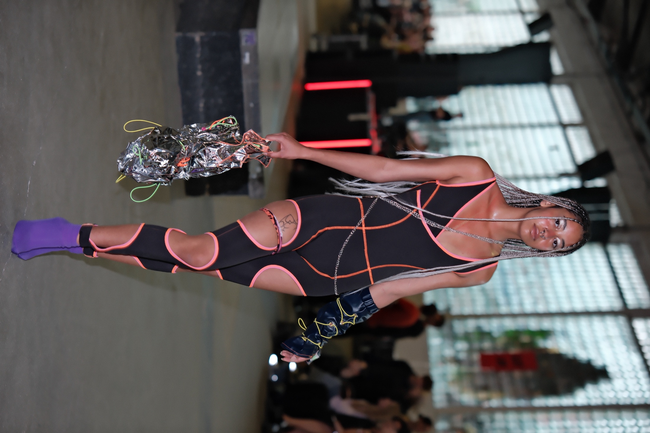 Runway look with black bodysuit, orange piping and purple shoes