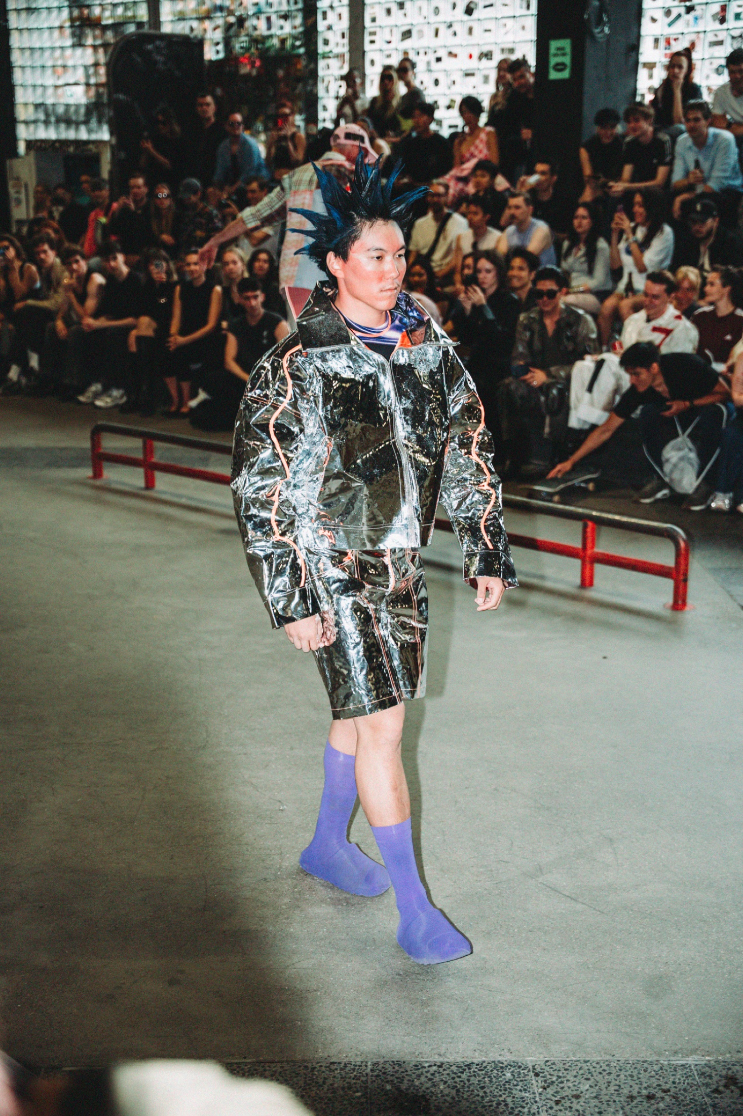 Runway look in a reflective silver jacket and purple shoes