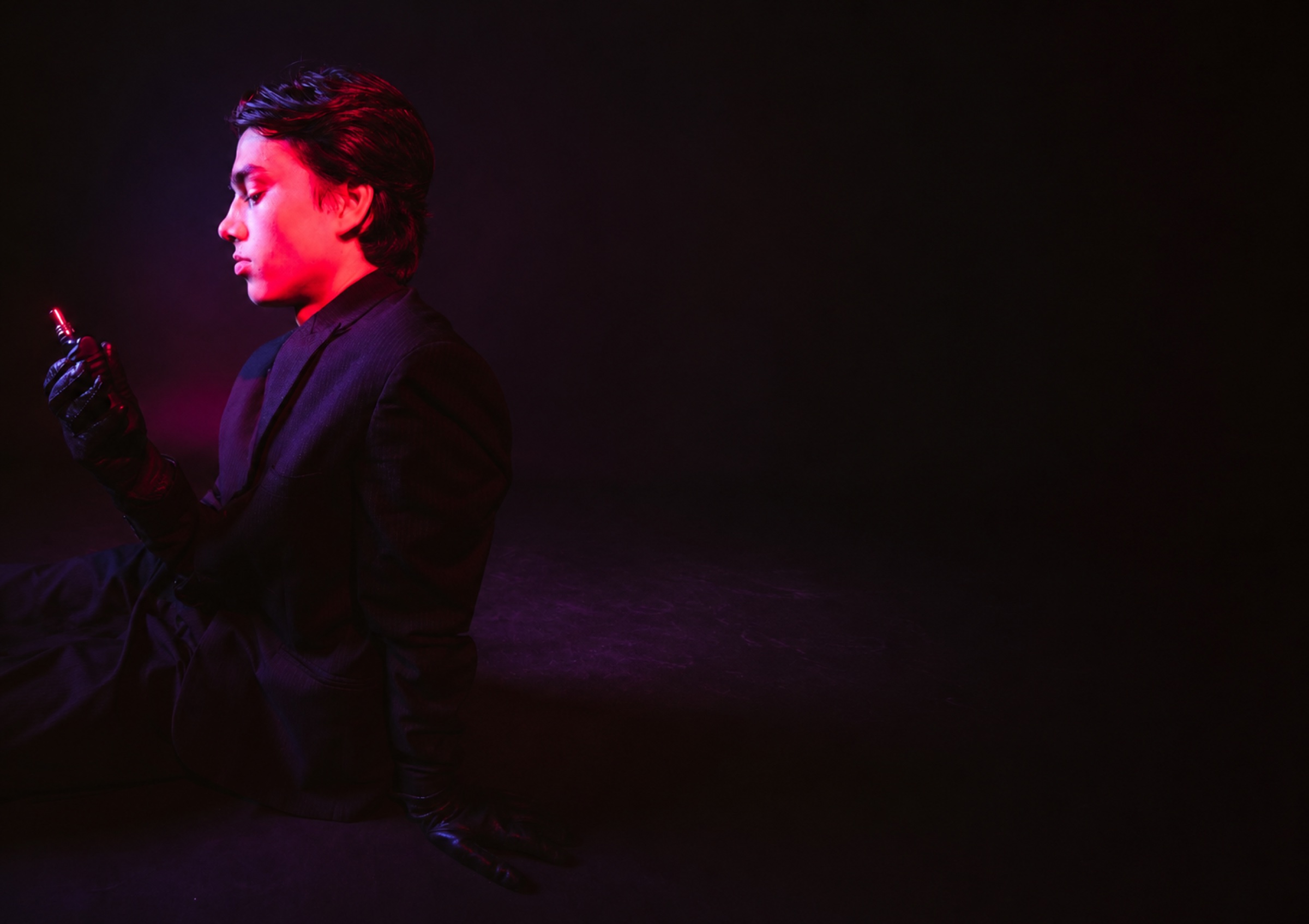 Profile portrait in dark tailoring under cinematic red and violet light